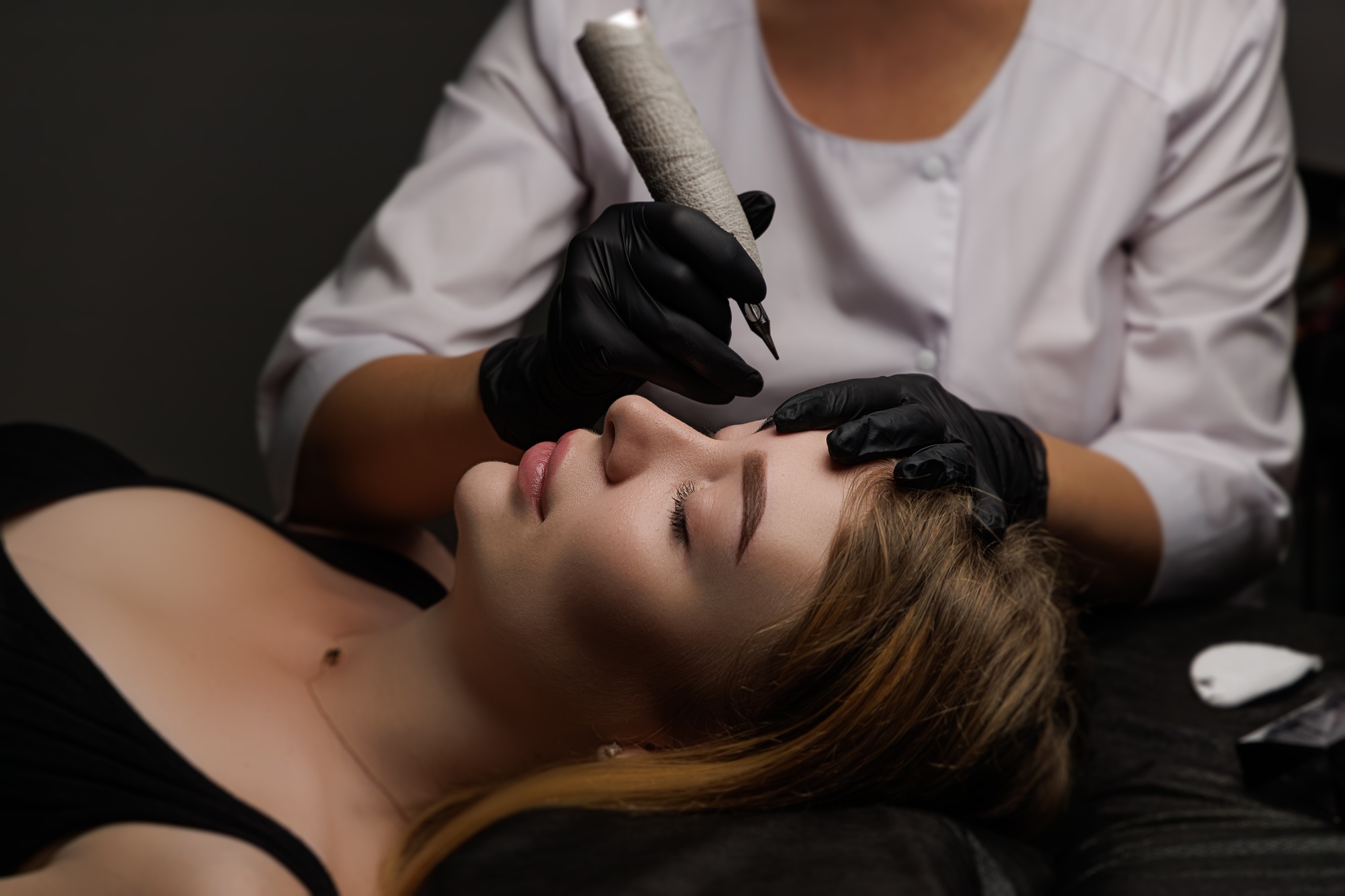 The technician applies precise strokes of pigment to enhance the client's eyebrows
