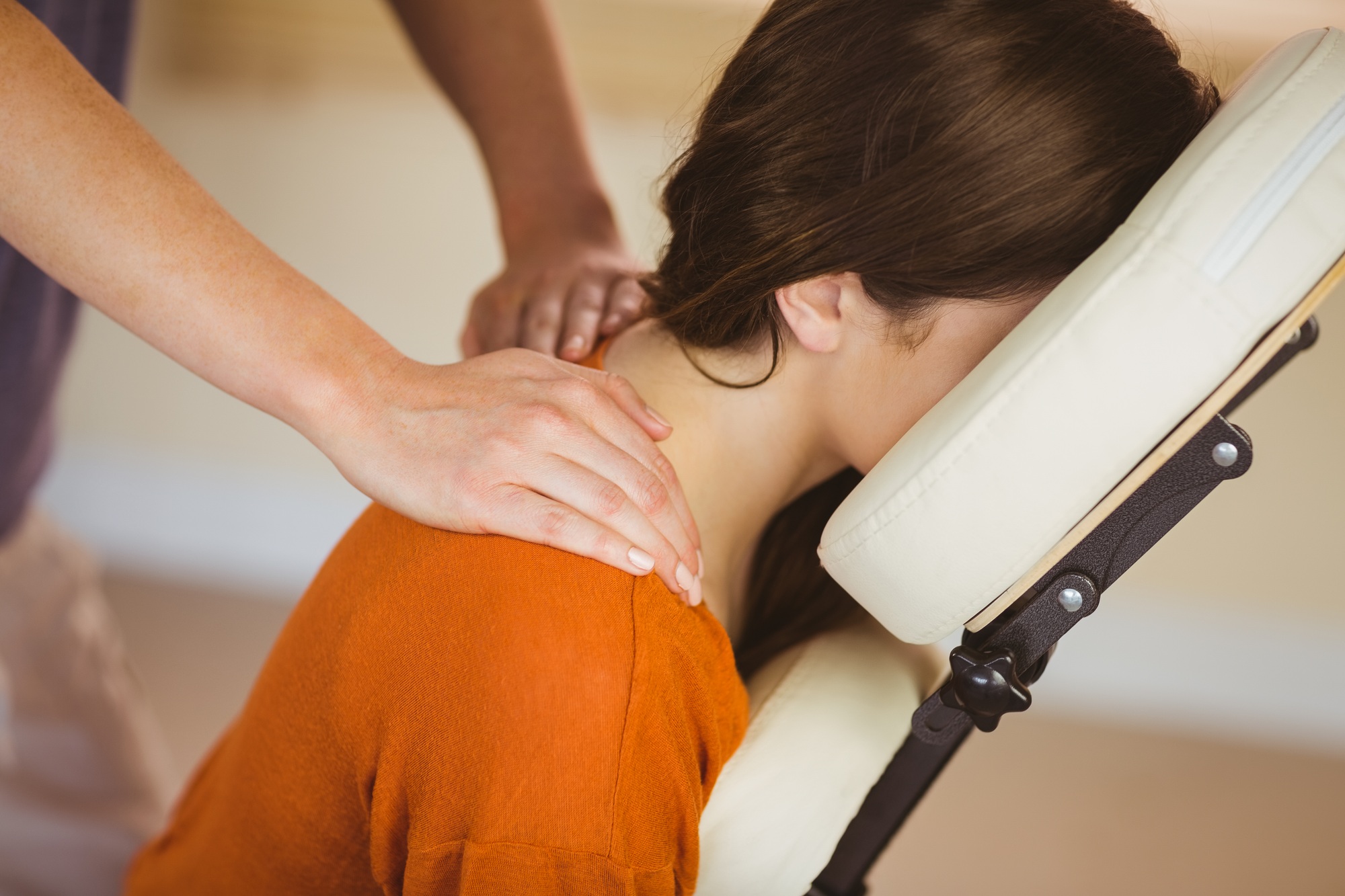 Young woman getting massage in chair in therapy room
